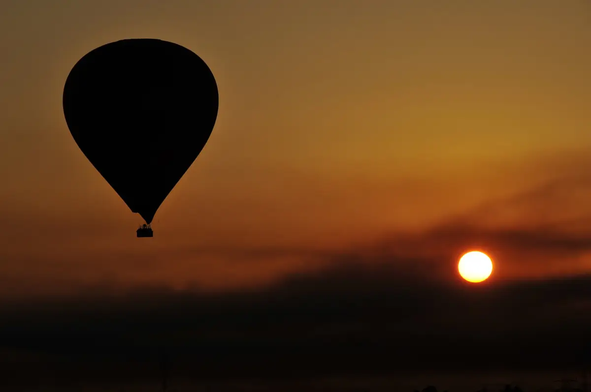 A balloon silhouetted against the rising sun over Luxor